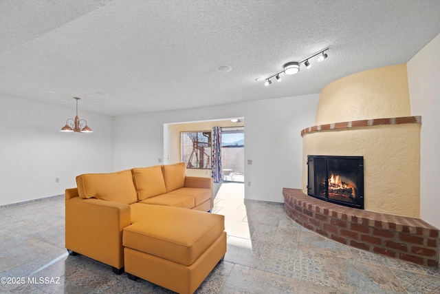 living room with a notable chandelier, a fireplace, and a textured ceiling