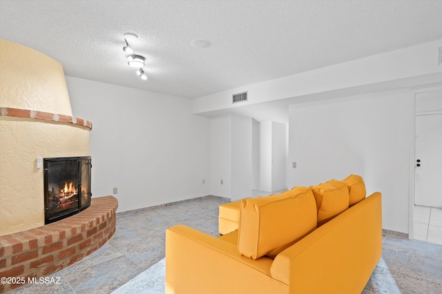 living room featuring a brick fireplace and a textured ceiling