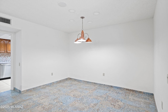 empty room featuring baseboards, stone finish flooring, visible vents, and a notable chandelier