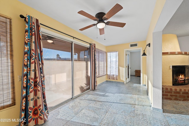 interior space with ceiling fan and a brick fireplace