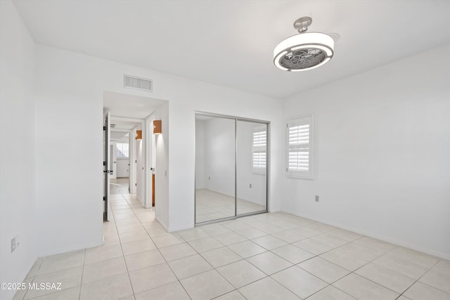 unfurnished bedroom with light tile patterned floors, a closet, and visible vents