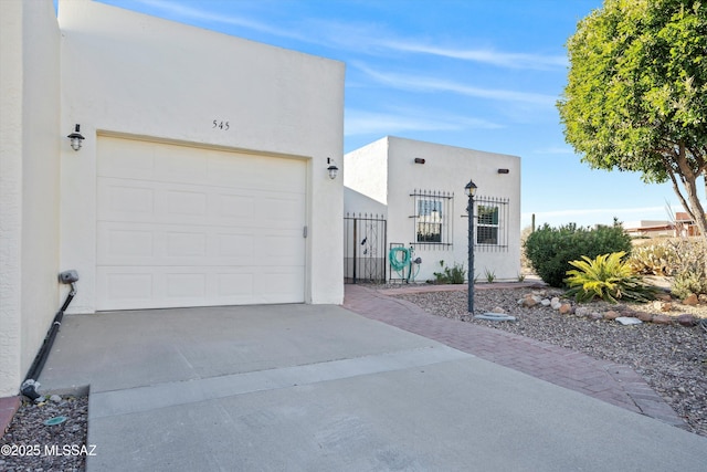 view of front facade with driveway, fence, an attached garage, and stucco siding