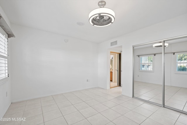 unfurnished bedroom featuring light tile patterned floors, visible vents, and a closet