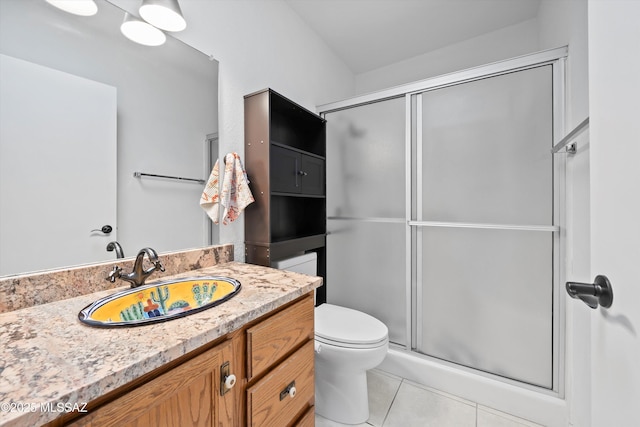 bathroom featuring tile patterned flooring, a shower with shower door, vanity, and toilet