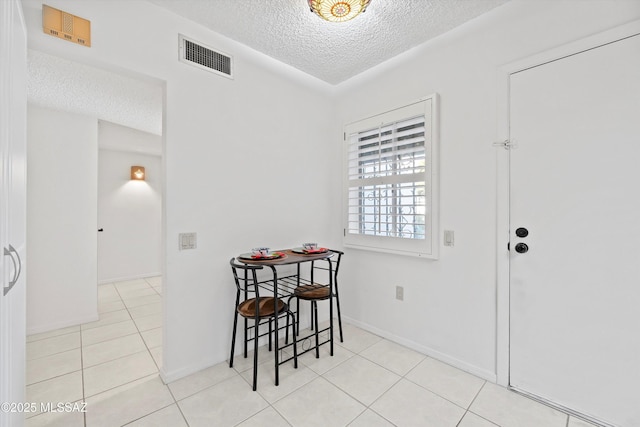 tiled dining space with a textured ceiling