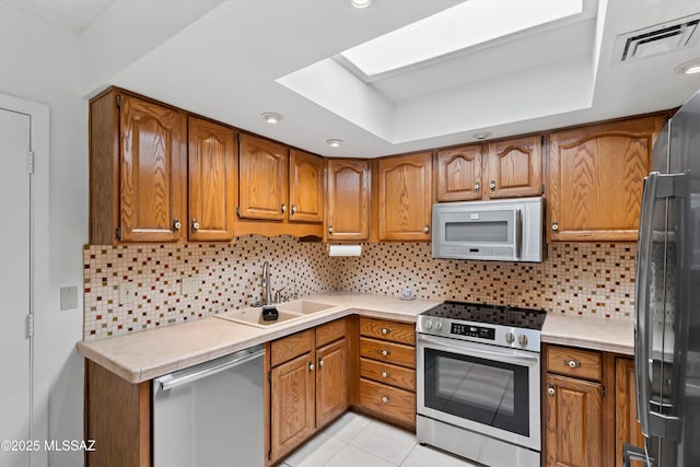 kitchen featuring sink, backsplash, stainless steel appliances, and light tile patterned floors