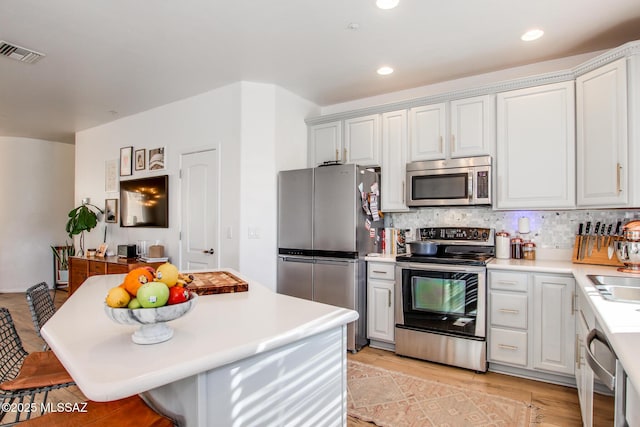 kitchen featuring a breakfast bar area, appliances with stainless steel finishes, white cabinets, and tasteful backsplash