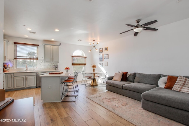 living room with ceiling fan, sink, and light wood-type flooring