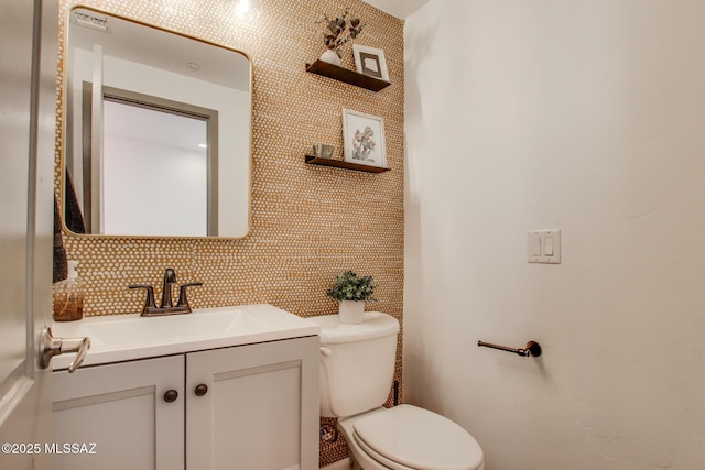 bathroom with toilet, backsplash, and vanity