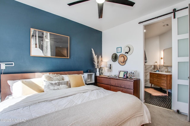 bedroom featuring ceiling fan, a barn door, carpet floors, and sink