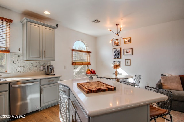 kitchen with gray cabinetry, dishwasher, backsplash, and a center island