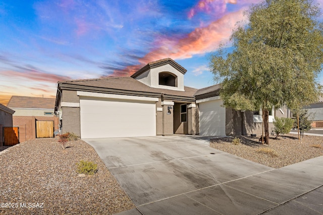 view of front of home featuring driveway, fence, an attached garage, and stucco siding