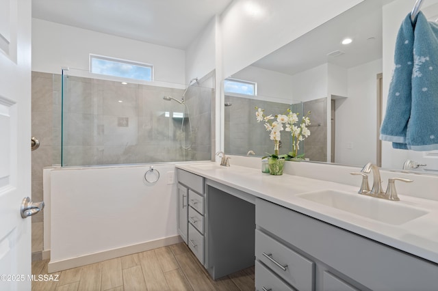 full bathroom featuring wood tiled floor, double vanity, a sink, and a walk in shower