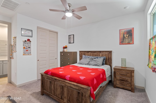 bedroom with a closet, light colored carpet, visible vents, ceiling fan, and baseboards