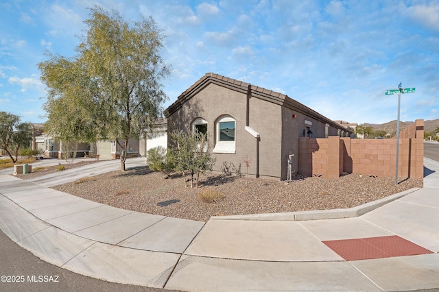 view of front of property with a tile roof, fence, and stucco siding