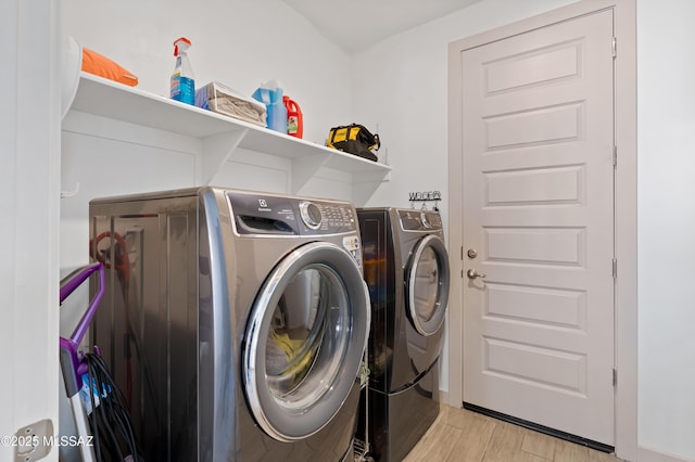 laundry area with laundry area, washer and clothes dryer, and light wood finished floors