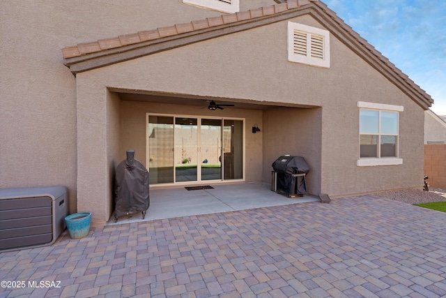 rear view of house featuring ceiling fan, a patio area, a tile roof, and stucco siding