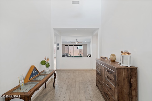 hall with light wood-type flooring, visible vents, and baseboards