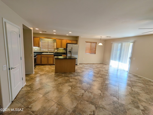 kitchen featuring ceiling fan, stainless steel appliances, tasteful backsplash, decorative light fixtures, and a center island