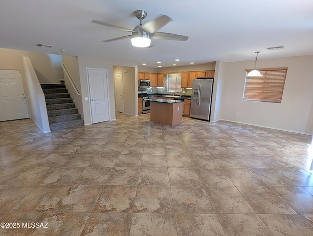 kitchen with ceiling fan, tasteful backsplash, a center island, hanging light fixtures, and stainless steel appliances