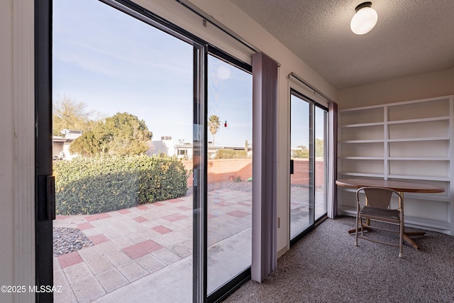 doorway to outside featuring carpet floors and a textured ceiling