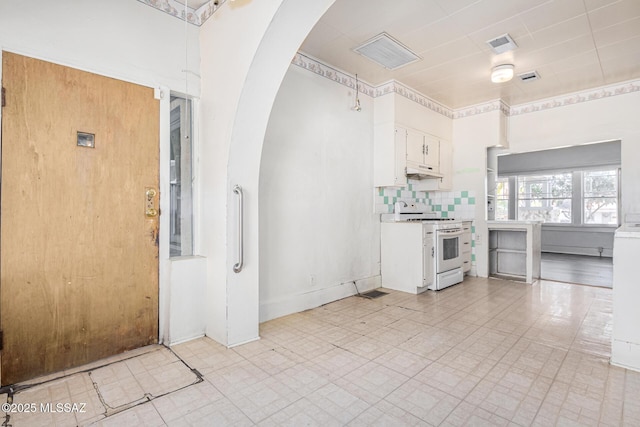 kitchen with tasteful backsplash, white cabinets, and white range oven