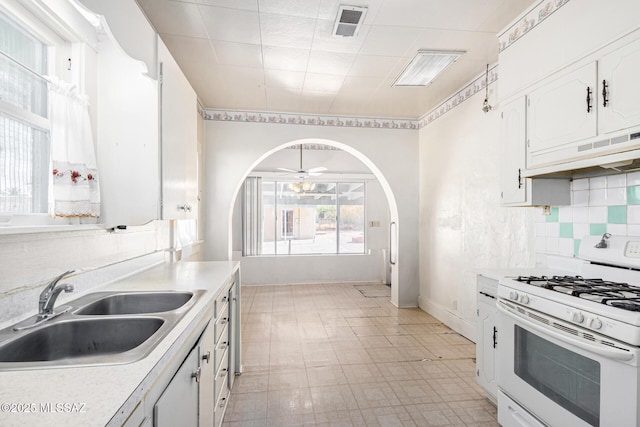 kitchen with white cabinetry, ceiling fan, backsplash, white gas range, and sink