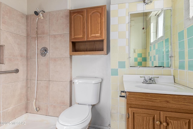 bathroom featuring toilet, decorative backsplash, a tile shower, and vanity