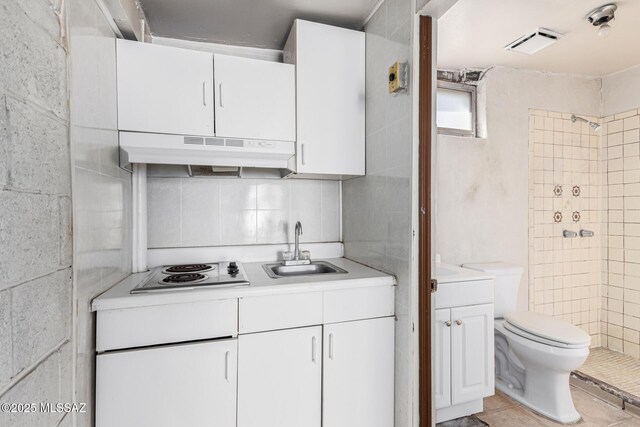 kitchen featuring tile walls, sink, white cabinetry, electric cooktop, and light tile patterned floors