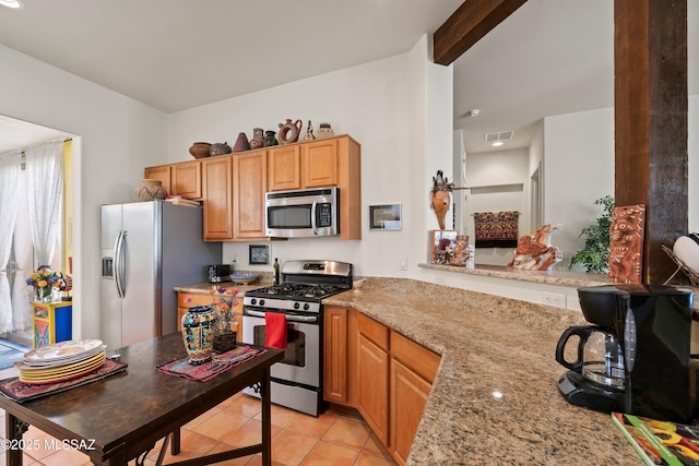 kitchen with kitchen peninsula, beamed ceiling, light stone countertops, appliances with stainless steel finishes, and light tile patterned floors