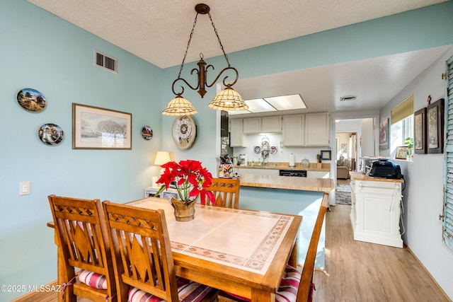 dining room featuring light wood-type flooring and a textured ceiling