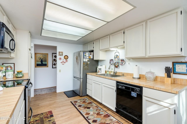 kitchen featuring white cabinets, sink, light hardwood / wood-style flooring, and black appliances