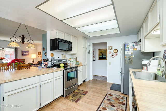 kitchen featuring sink, white cabinetry, decorative light fixtures, appliances with stainless steel finishes, and light hardwood / wood-style floors