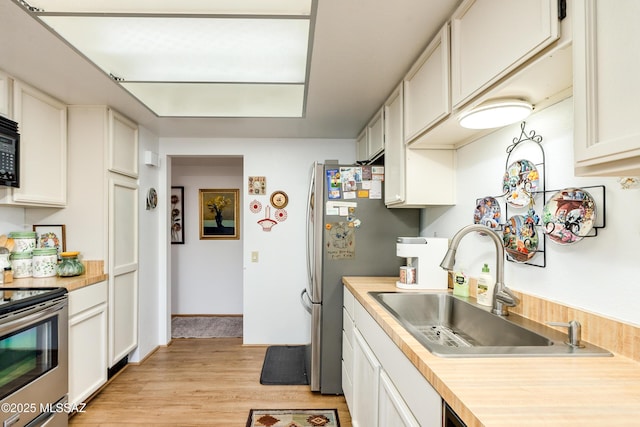 kitchen featuring sink, light hardwood / wood-style flooring, stainless steel appliances, and white cabinets