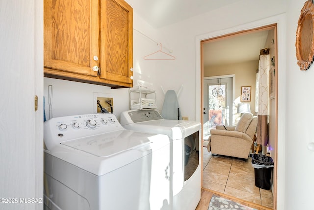 laundry area featuring light tile patterned flooring, cabinets, and washer and clothes dryer