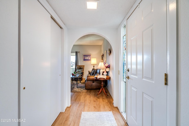 hallway with a textured ceiling and light wood-type flooring