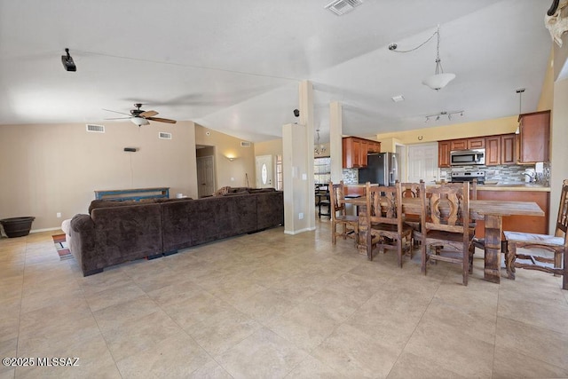 dining space with ceiling fan, track lighting, and lofted ceiling