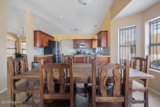 tiled dining area featuring lofted ceiling, an inviting chandelier, and rail lighting