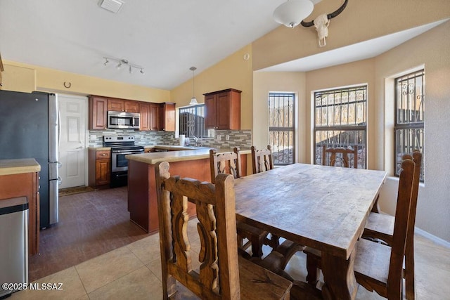 dining area with vaulted ceiling, light tile patterned flooring, and sink