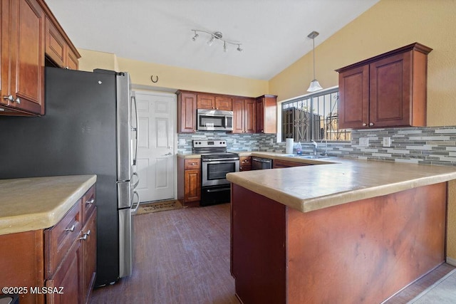 kitchen with kitchen peninsula, decorative backsplash, sink, hanging light fixtures, and stainless steel appliances