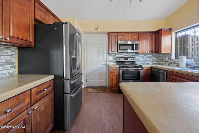 kitchen with tasteful backsplash, appliances with stainless steel finishes, sink, and dark hardwood / wood-style floors