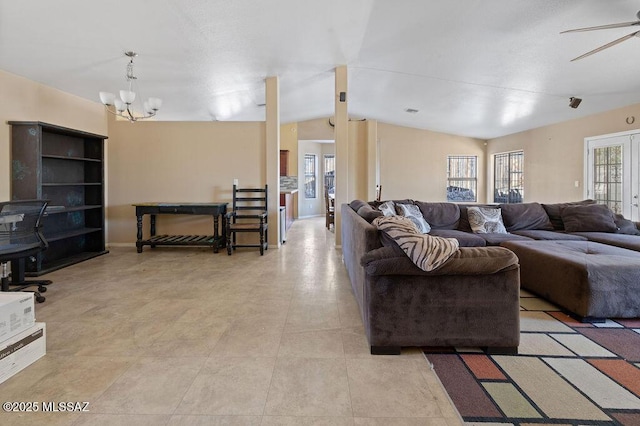 living room featuring ceiling fan with notable chandelier and vaulted ceiling