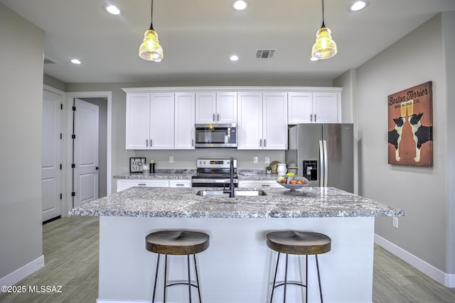 kitchen featuring pendant lighting, appliances with stainless steel finishes, and white cabinets