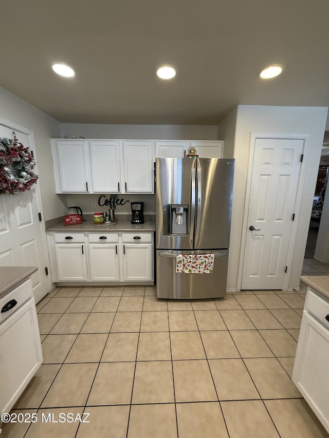 kitchen with light tile patterned flooring, white cabinets, and stainless steel fridge