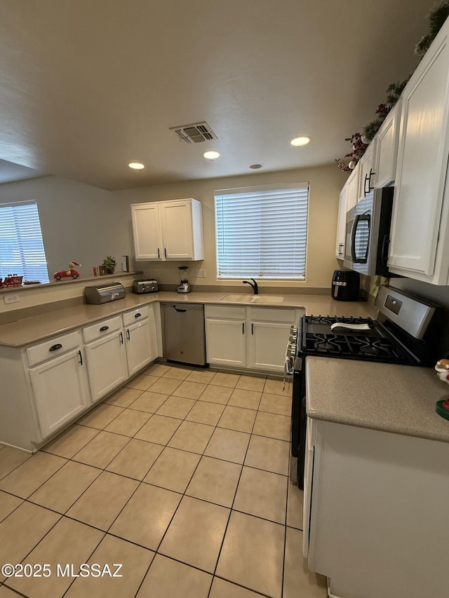 kitchen with sink, white cabinets, light tile patterned floors, and appliances with stainless steel finishes