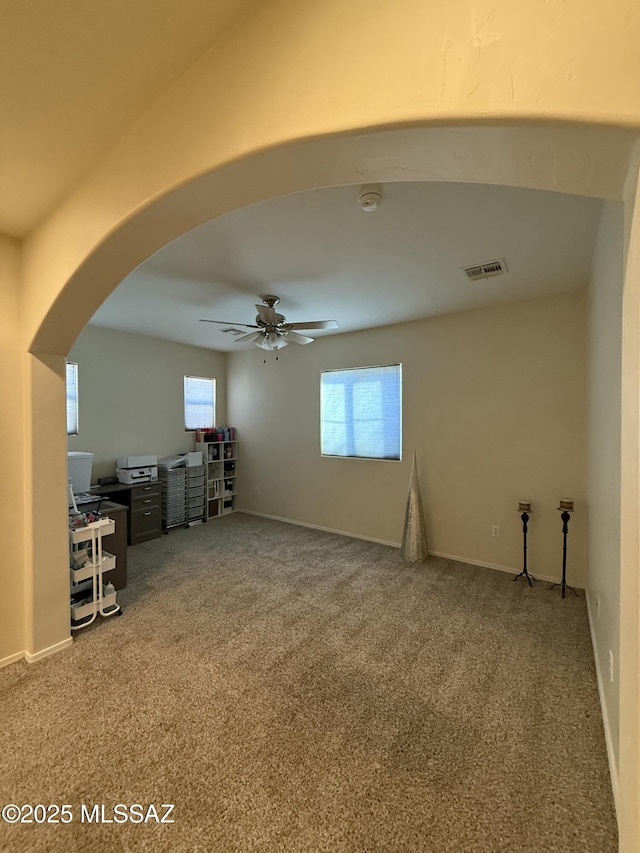 unfurnished living room with ceiling fan and carpet