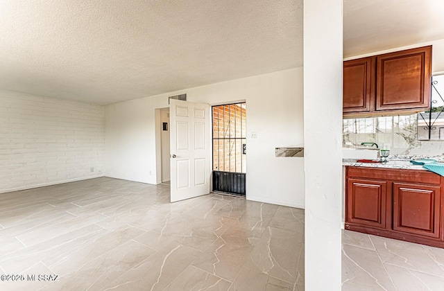 kitchen featuring brick wall and a textured ceiling