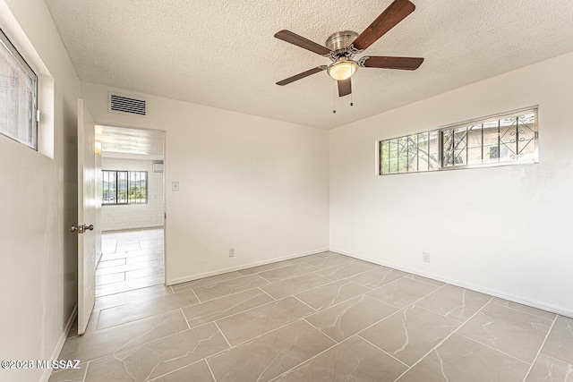 spare room with a textured ceiling and ceiling fan