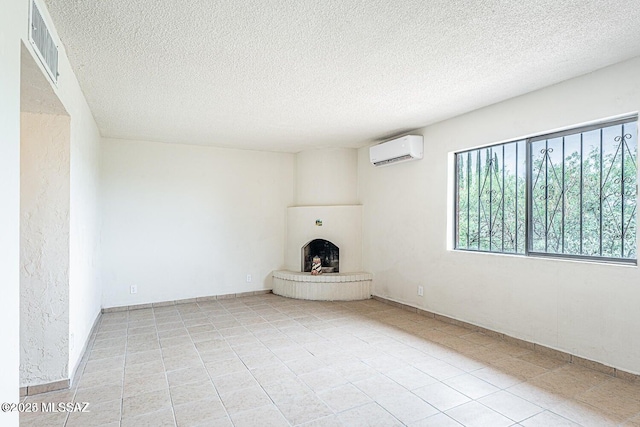 unfurnished living room with a textured ceiling, a large fireplace, a wall mounted AC, and light tile patterned flooring