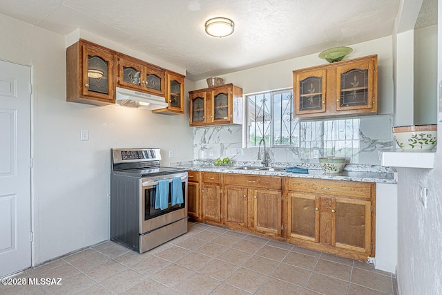 kitchen featuring stainless steel range with electric cooktop, light tile patterned flooring, backsplash, and sink